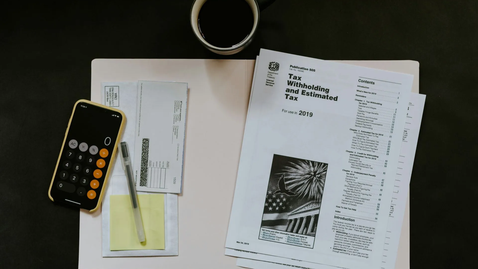 A desk with tax documents, a coffee cup, a smartphone calculator, and sticky notes—suggesting financial planning or tax preparation for a Commercial Roofing business in The Woodlands.
