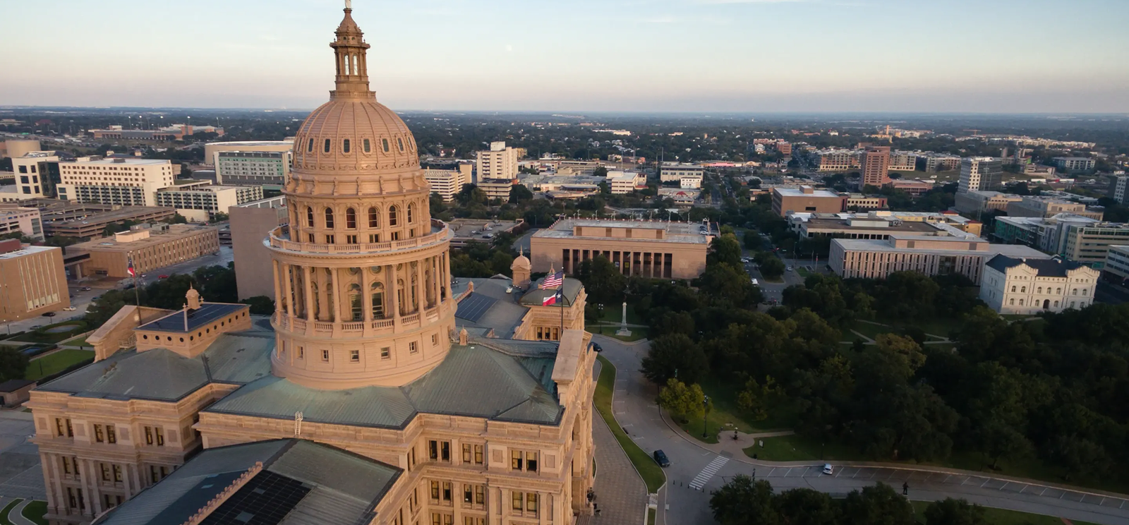 Aerial view of the Texas State Capitol building in Austin, showcasing its large dome and surrounding government and city buildings under a clear sky—an inspiring sight for Commercial Roofing professionals like Noble Roofing, serving areas such as The Woodlands.